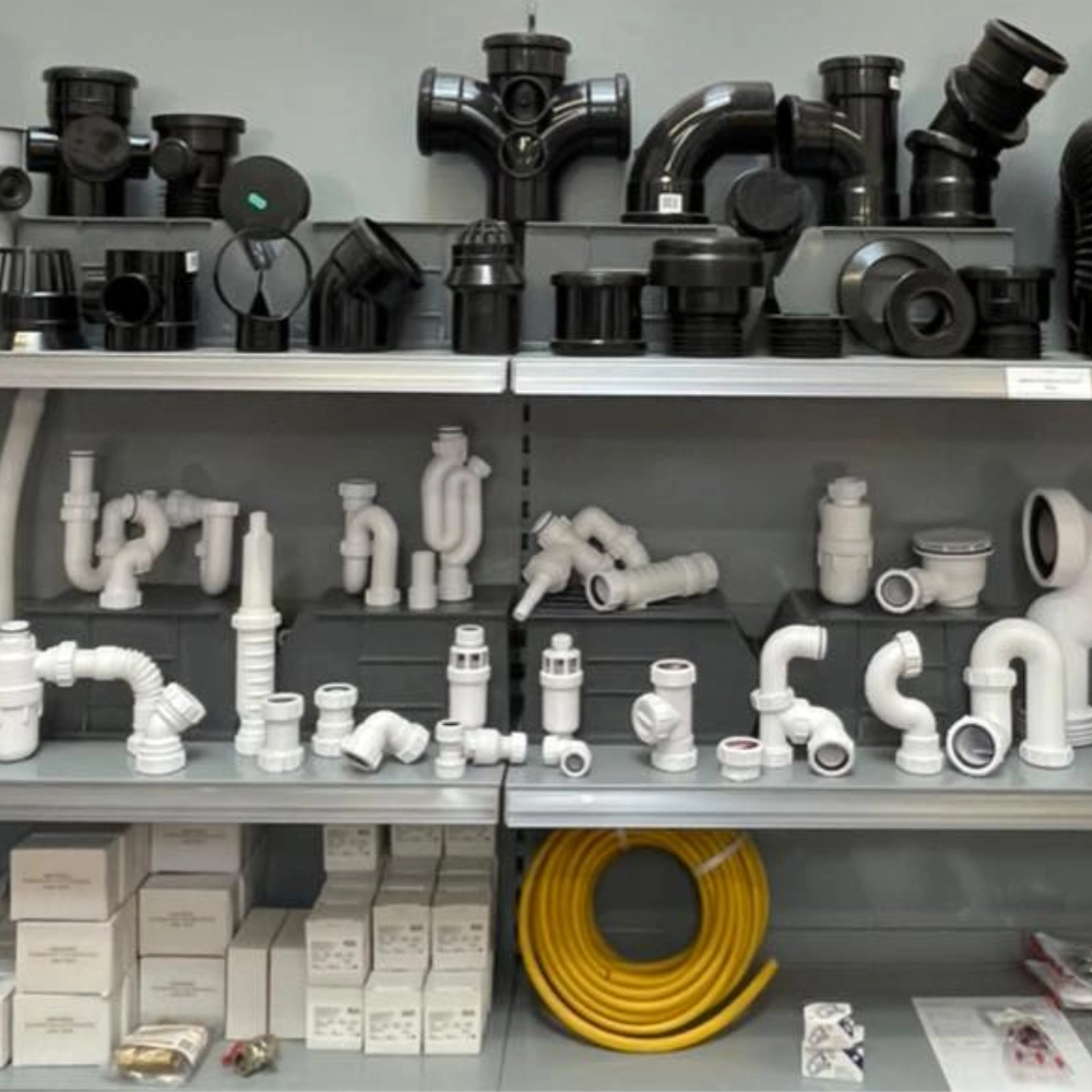 Display shelves stocked with heating pipe fittings, waste fittings, boxed parts and coiled pipework at Orange Heating Supplies.