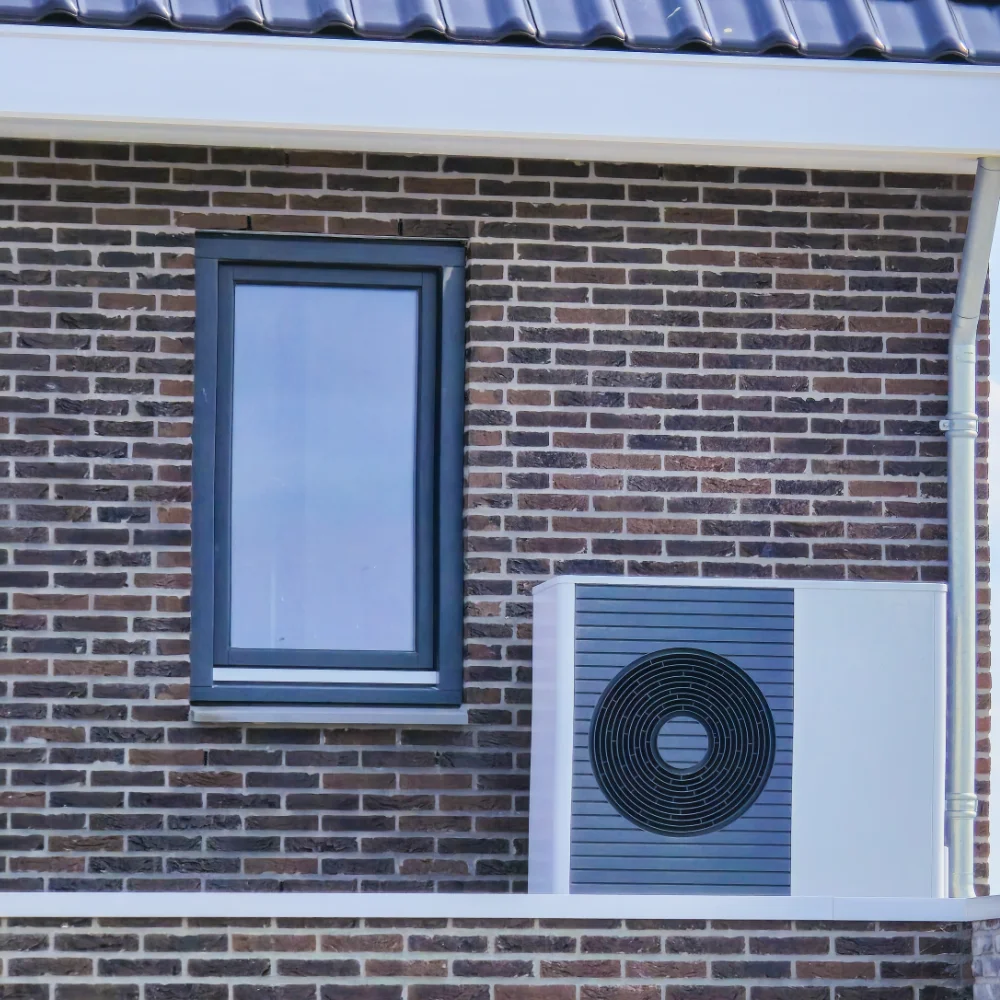 Outdoor heat pump unit installed outside a brick residential property.