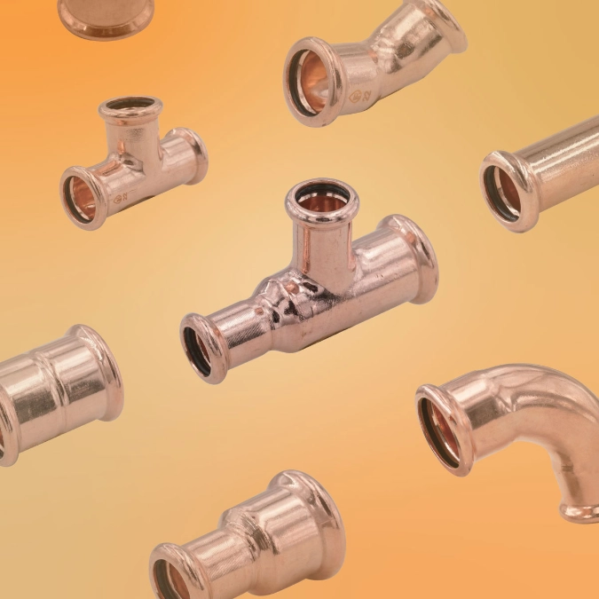 Assorted copper press fittings, including tees, elbows and couplings, displayed on an orange background.